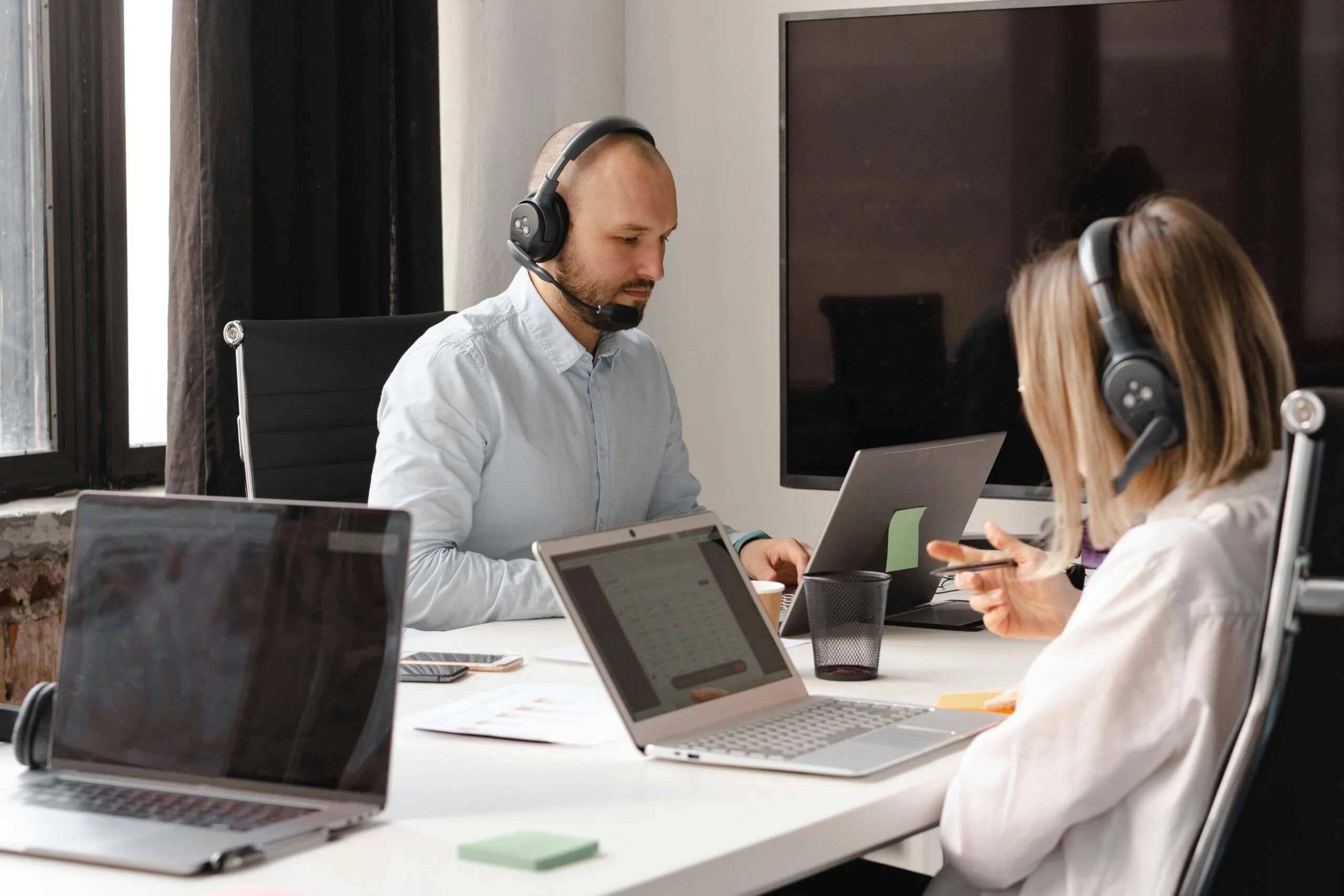 Call center agent with headset working on a laptop during a negotiation
